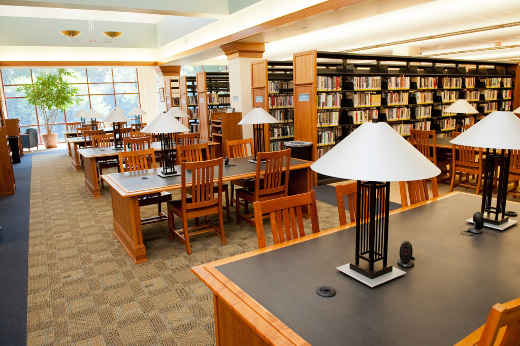 A bright and inviting photo of the second floor stacks and study tables.