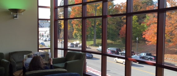 A patron reading the newspaper near the window at the library.