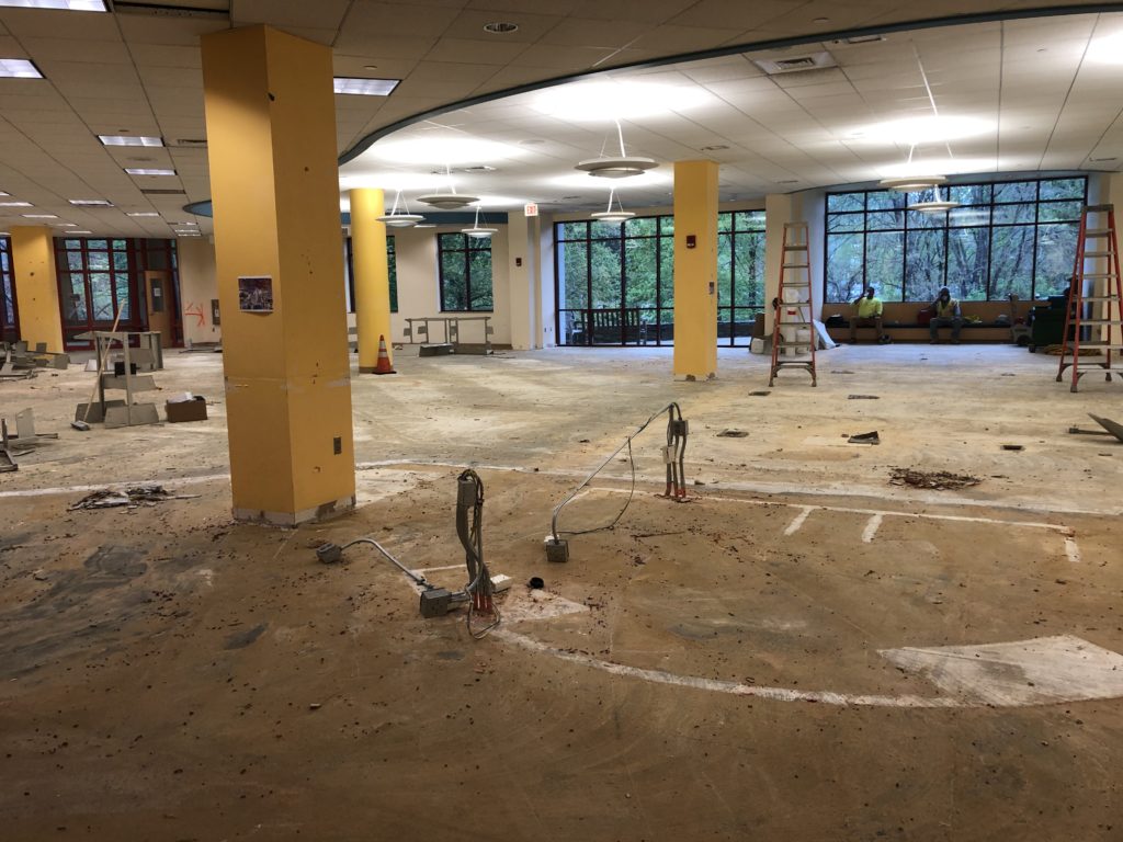 The old children's room with the carpet stripped away. The floor is particularly dirty and there are some disassembled metal shelves in the background.