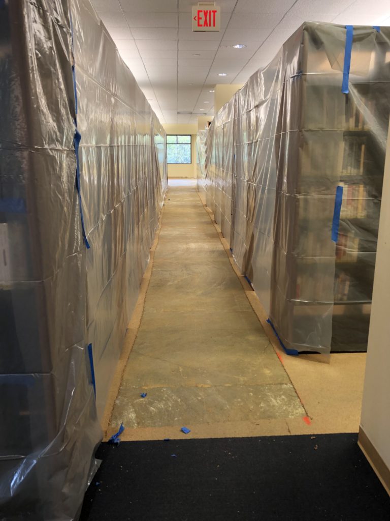 The second floor stacks, with books still on the shelves, covered loosely in plastic tarp to protect from construction-related damage.