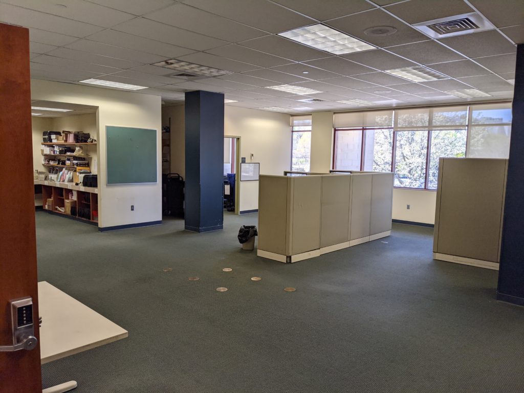 A barren office space that once would have held many many blue carts loaded with books and other items. 