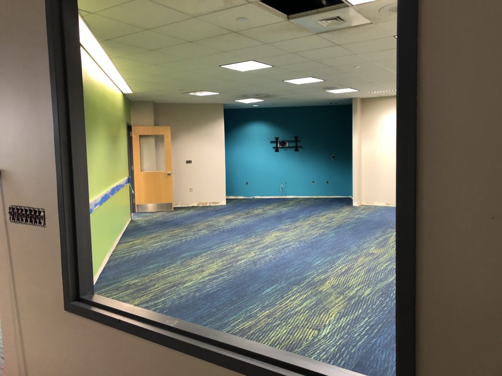 A view looking into the Middle School Room, which now has a colorful, mottled blue and green carpet to match the walls.