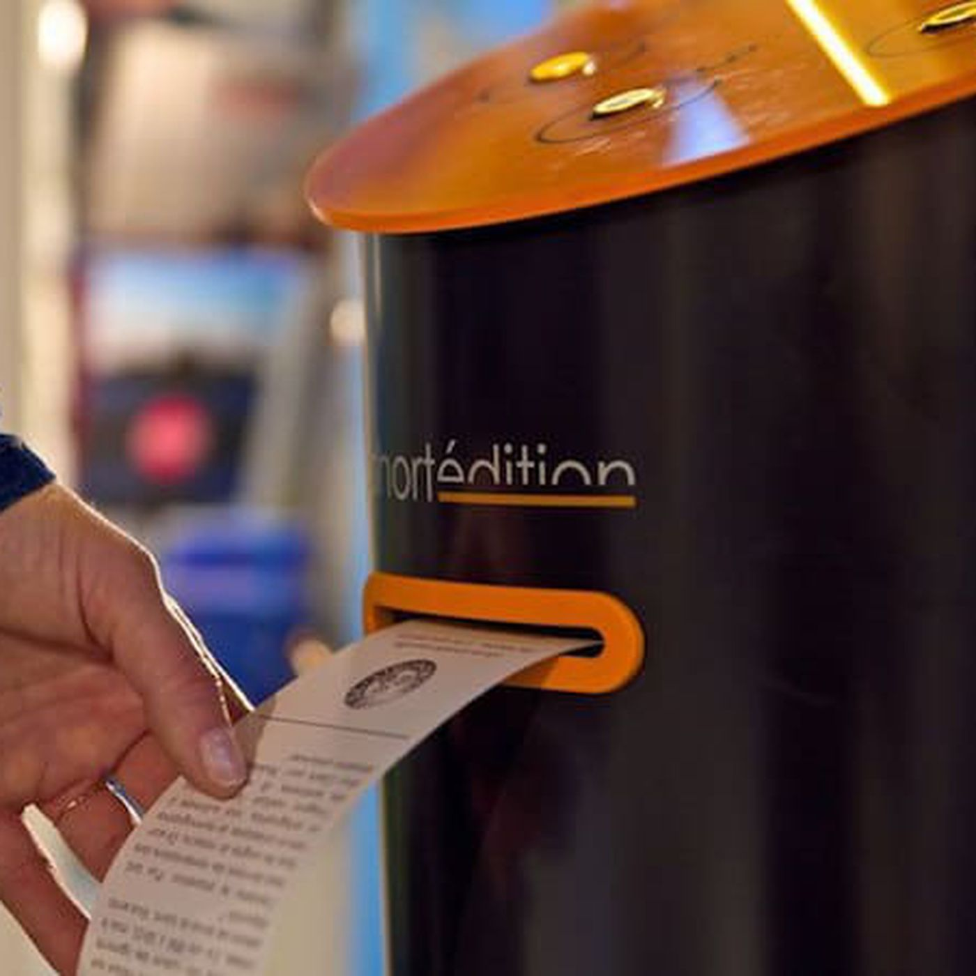 A closeup on the Short Story dispenser. After choosing from one of the three types, it will be printed like a receipt for you to take home.