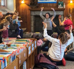 Hills branch storytime - grown-ups and children all copying the librarian by waving their hands in the air