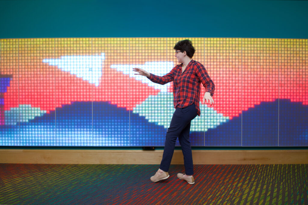 A librarian playing with the new LUMES wall. The game on the display lets you send paper planes flying across the wall.