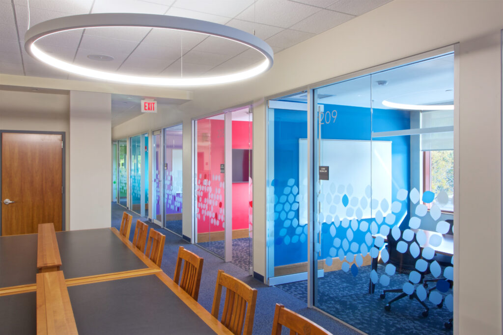 The newly-renovated conference rooms. Each room is painted in a different, bright color, and has both a whiteboard and a screen inside. The walls and doors are glass, allowing lots of light through.