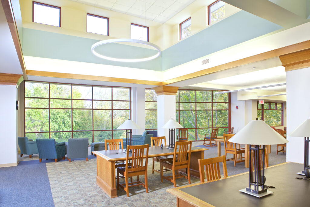 The view of Simon's Park from the second floor seating area. There are more cushioned chairs facing the park and a large working desk with regular wooden chairs. The space feels very open.