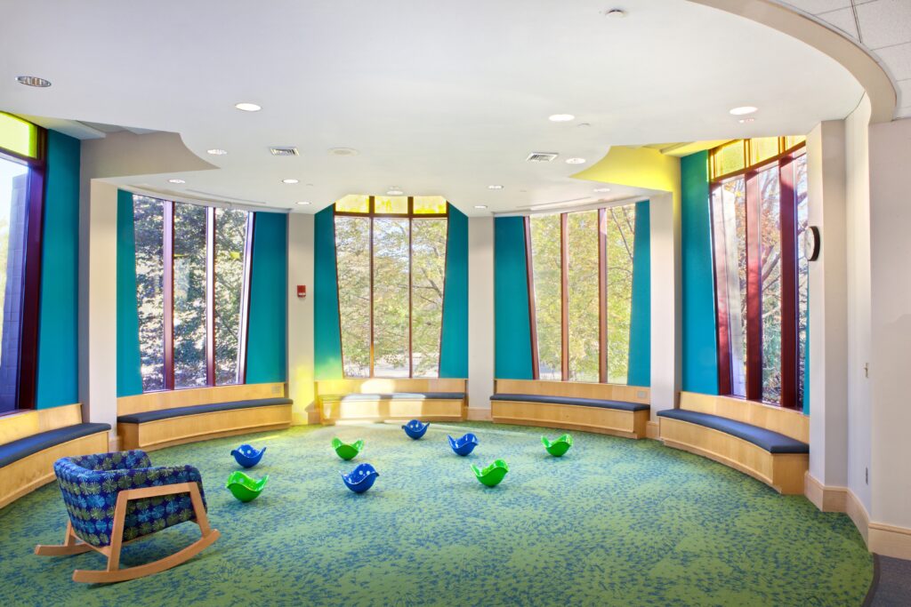 The round Storytime Room, showing off bench seating around the outside of the room, and small plastic shell seats for children to use on the floor.