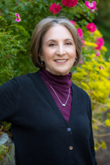 photo of Dr. Bernice Lerner standing in front of floral shrubbery. 