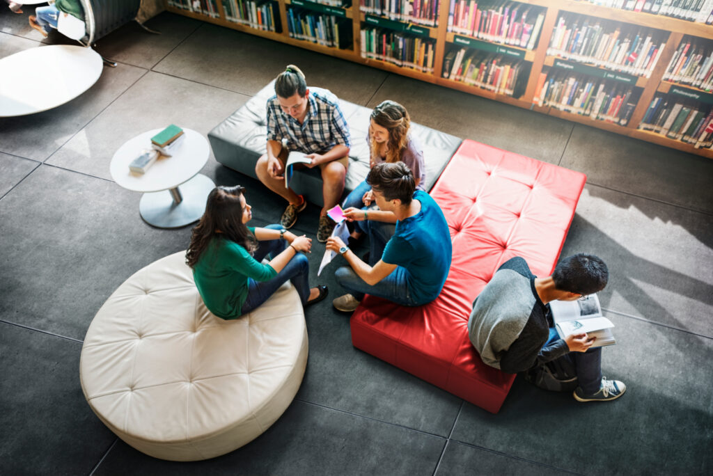 Teens gathered in a seating area in the library, talking with eachother